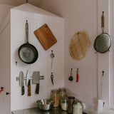 Kitchen wall with iron pan, chopping board and knifes hanging on the wall. 