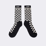 Pair of black and cream checkerboard socks with NOM*d logo cuffs, laid flat on a light background