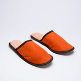 Pair of orange lambskin slippers with cream wool lining, on a white background